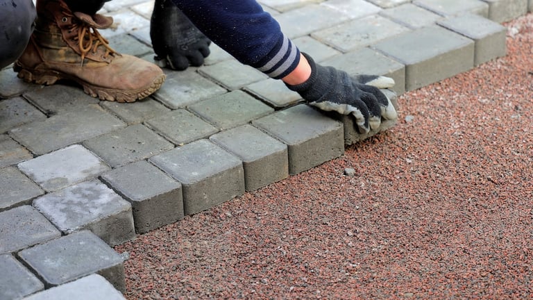 Worker laying block paving