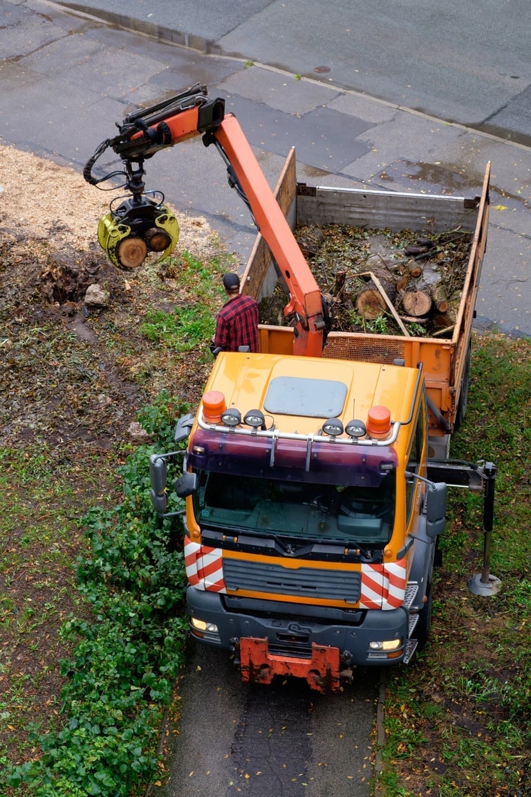 Orange utility truck with extending crane arm parked on wet street, overhead view